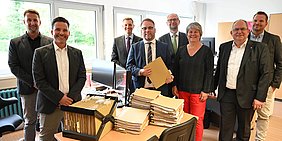 Gruppenfoto mit Stapel von BAfoeG-Akten auf Schreibtisch