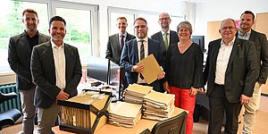 Gruppenfoto mit Stapel von BAfoeG-Akten auf Schreibtisch