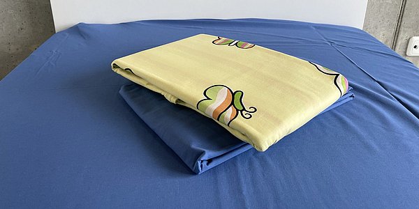 Ein Foto von den Inhalten des Starterpakets Nr. 3. Zu sehen sind Bettbezug und Spannbetttuch, die auf einem Bett liegen.