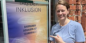 Foto: Sozialberaterin Concetta Mugavero neben Plakat zum Aktionstag Inklusion