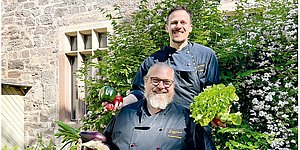 Foto: Zwei Koeche vom Team Mensa Witzenhausen vor Mensa-Gebaeude