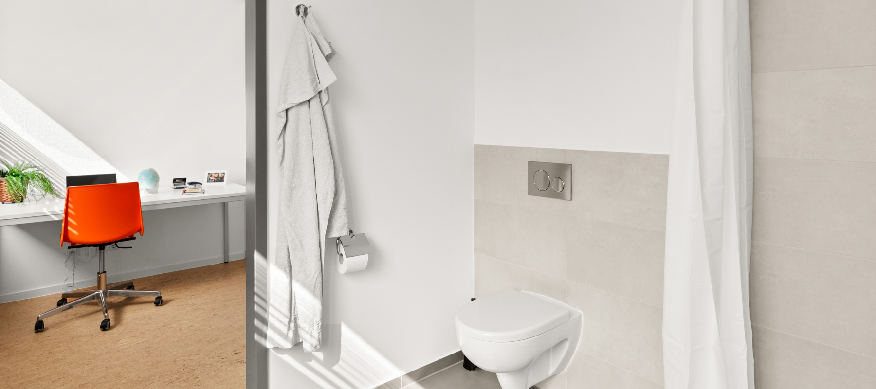 Blick aus dem Bad in ein Einzelzimmer. Zu sehen ist auch die Toilette im Bad.