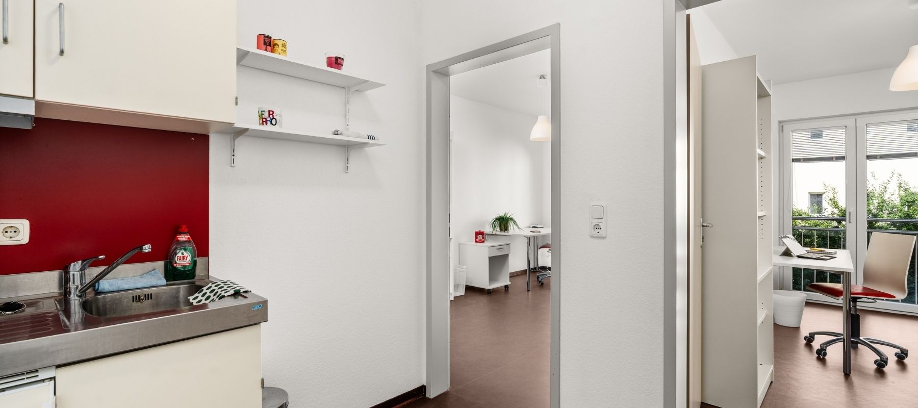 Foto aus einem Doppelapartment. Zu sehen ist der Küchenbereich mit den Türen zu beiden Zimmern.