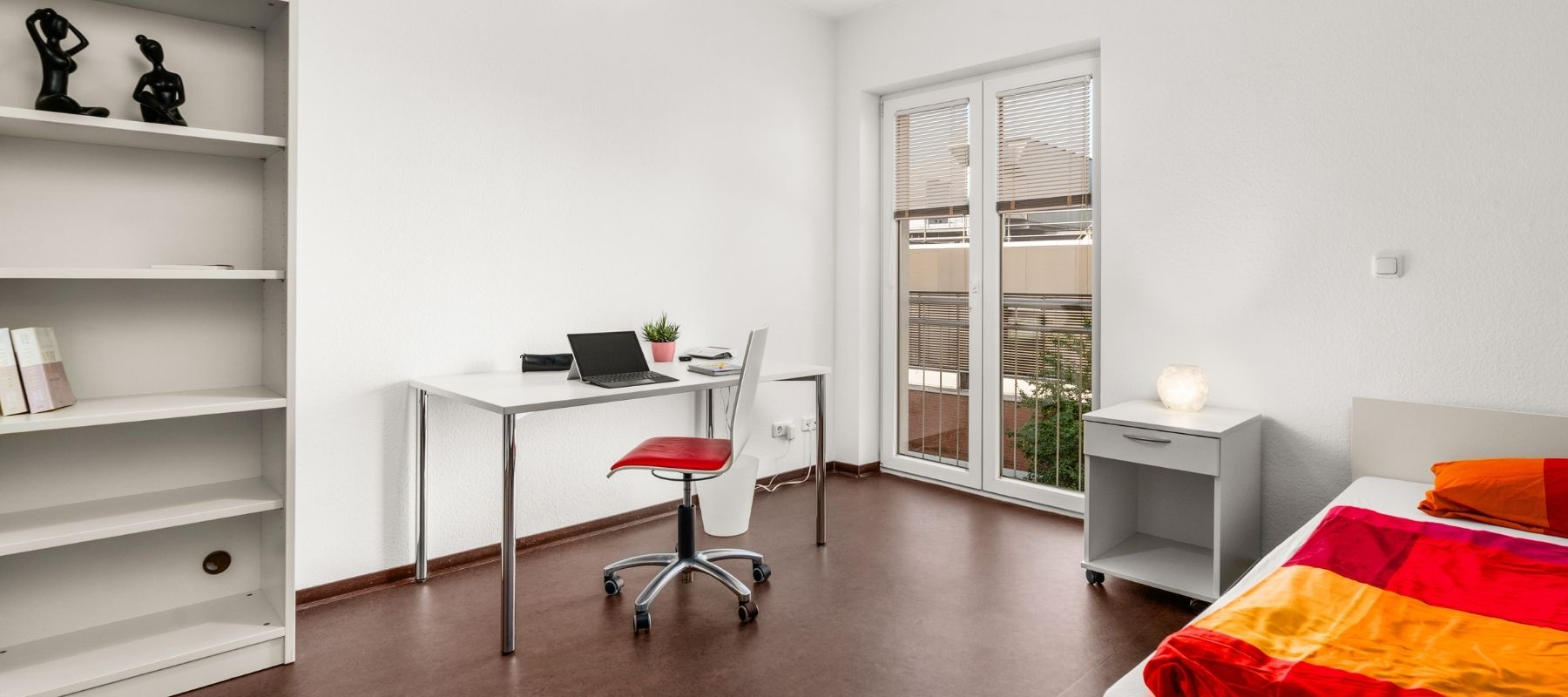 Foto aus dem Zimmer eines Doppelapartments. Zu sehen ist ein Schreibtisch mit Stuhl.
