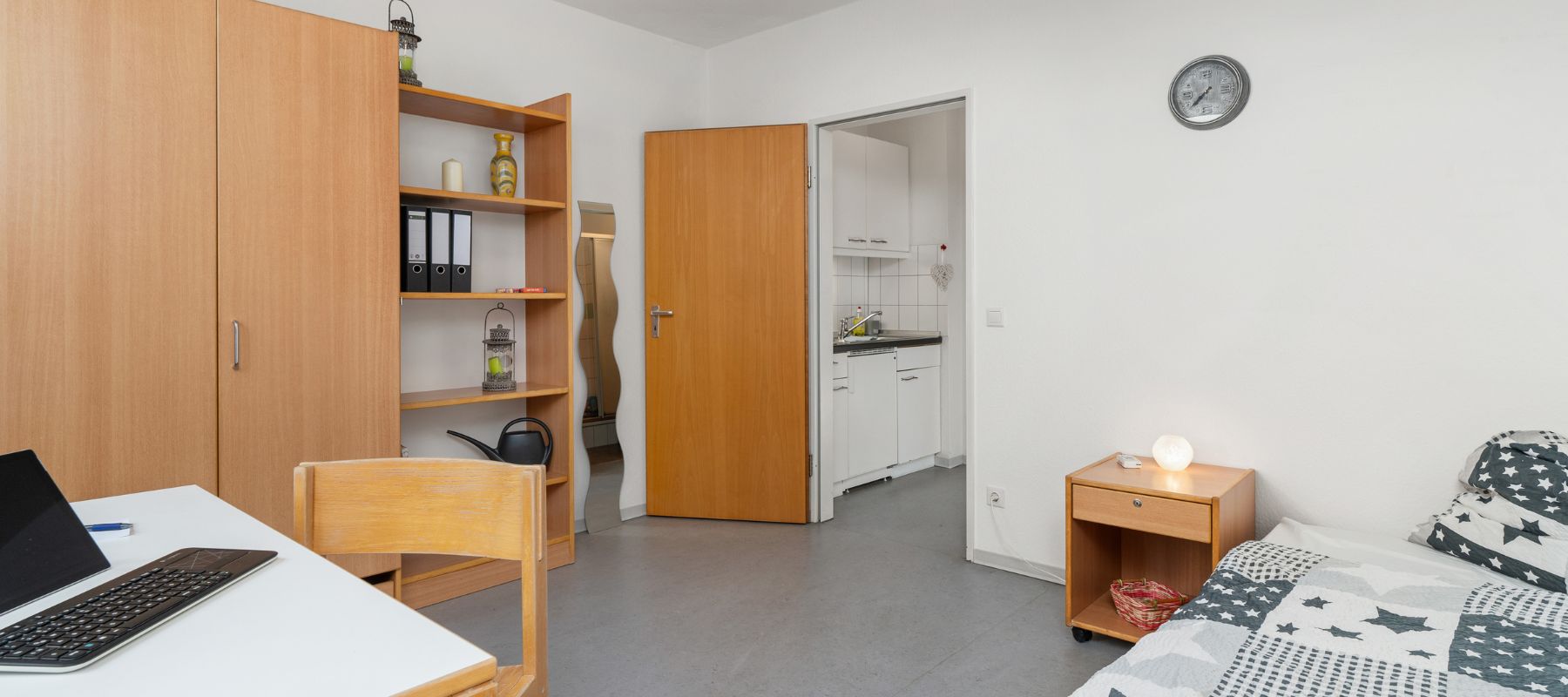 Foto eines Einzelapartments mit Schrank, Bett und Schreibtisch.