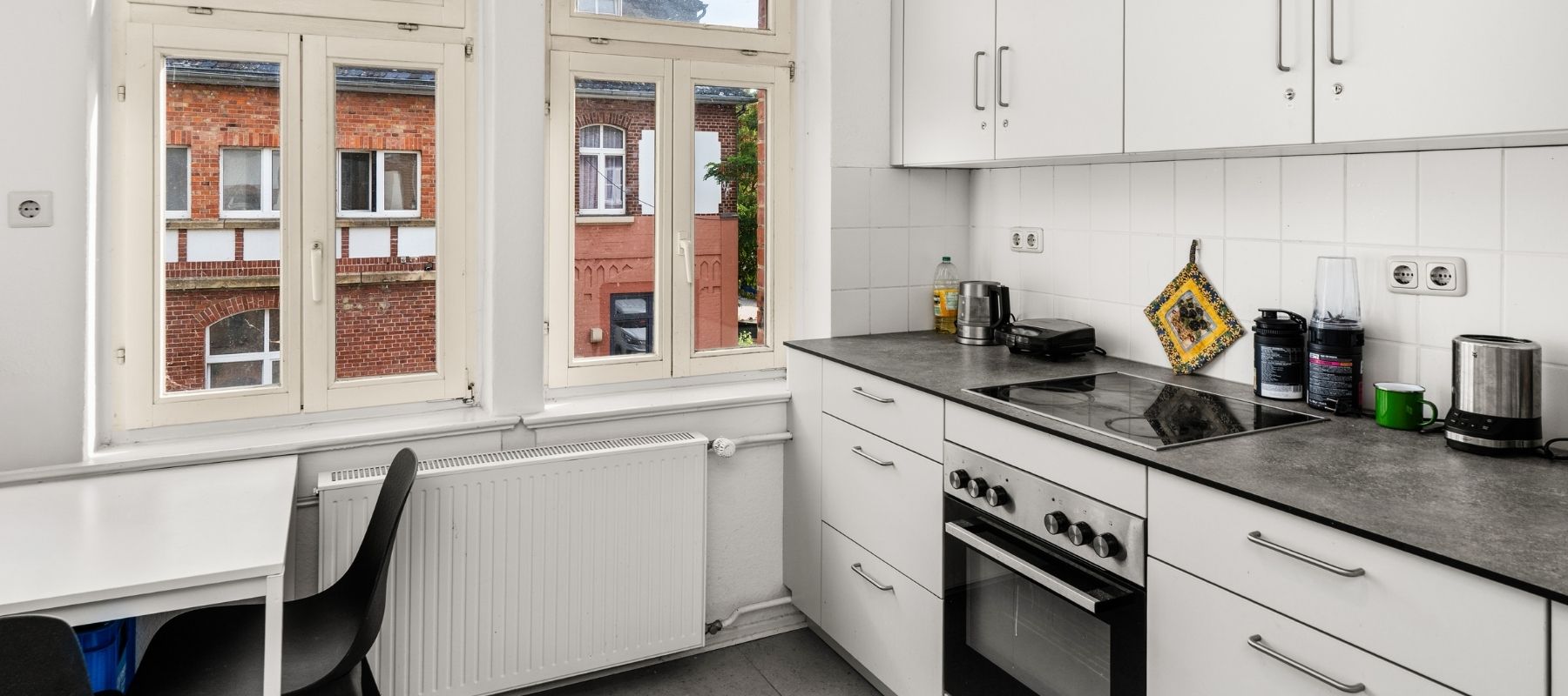 Helle WG-Küche in der Hegelsbergstraße 22. Zu sehen ist die Küchenzeile, dazu ein kleiner Tisch mit Stühlen.