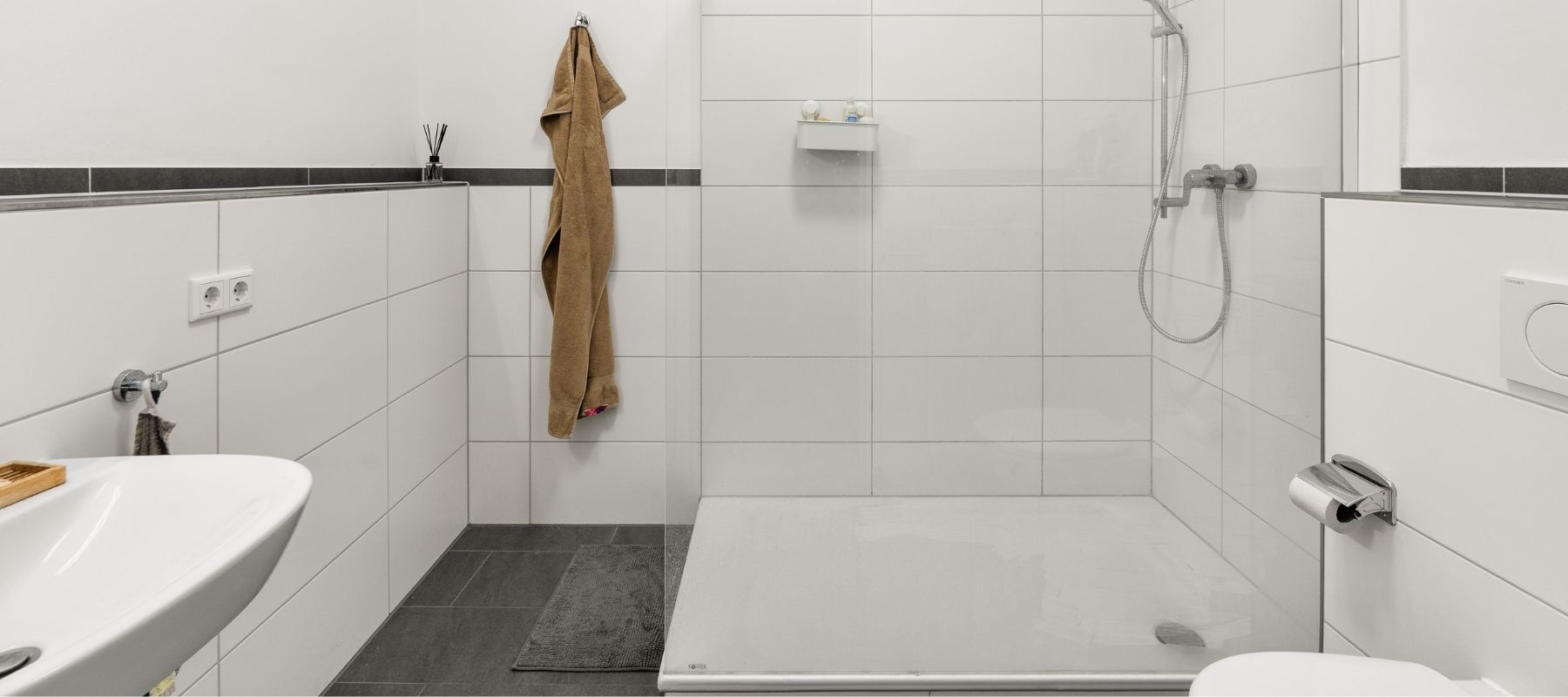 WG-Bad in der Hegelsbergstraße 22. Zu sehen sind eine große Dusche, ein Waschbecken und eine Toilette.