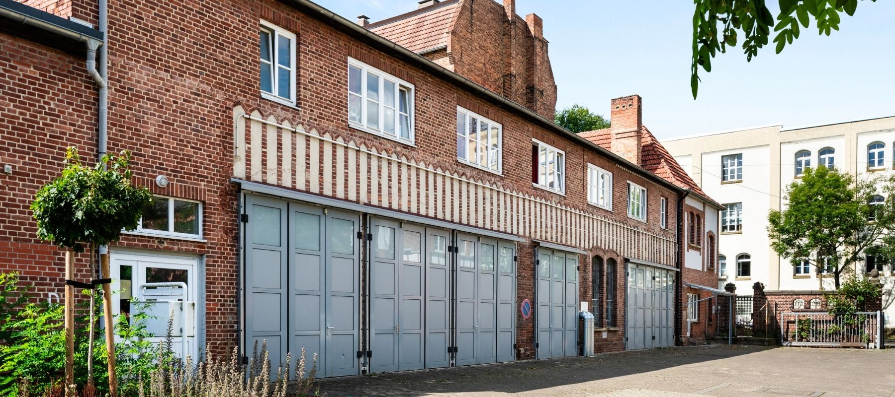 Vorderseite der Hegelsbergstraße 22a. Zu sehen ist ein altes Industriegebäude. Unten sind Garagen. Darüber die Wohnungen der 22a.