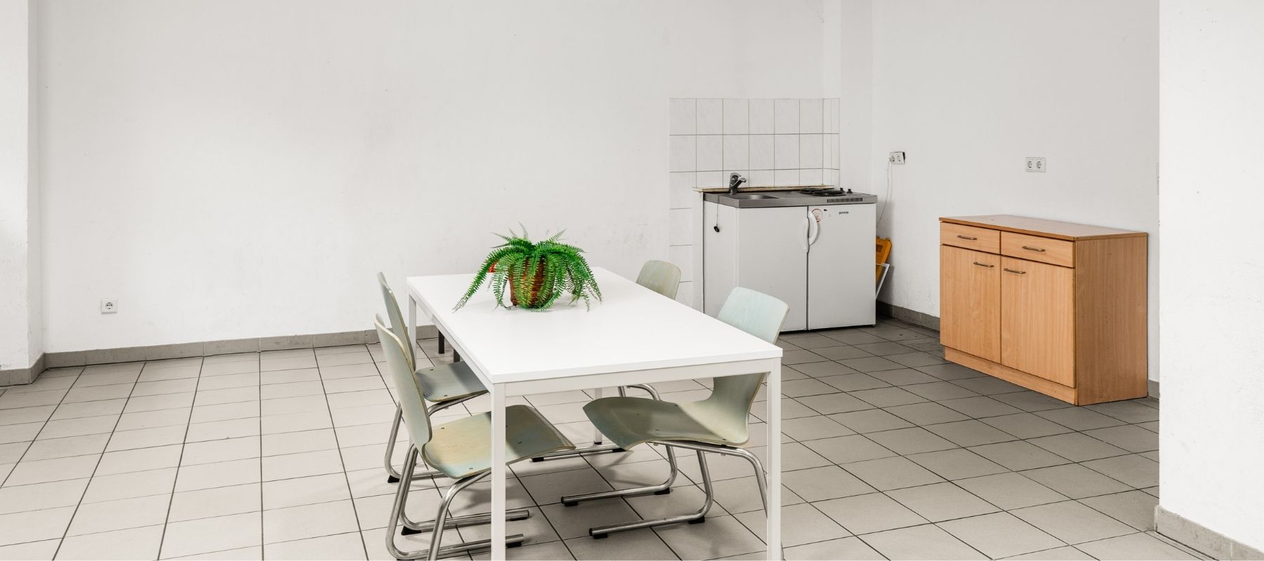 Gemeinschaftsraum in der Hegelsbergstraße 24 mit Tisch, Stühlen und kleiner Spüle.