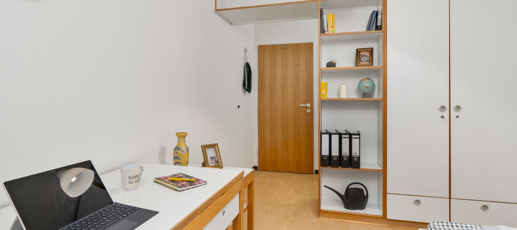 Einzelzimmer in WG: Blick vom Schreibtisch am Bücherregal vorbei auf die Zimmertüre.
