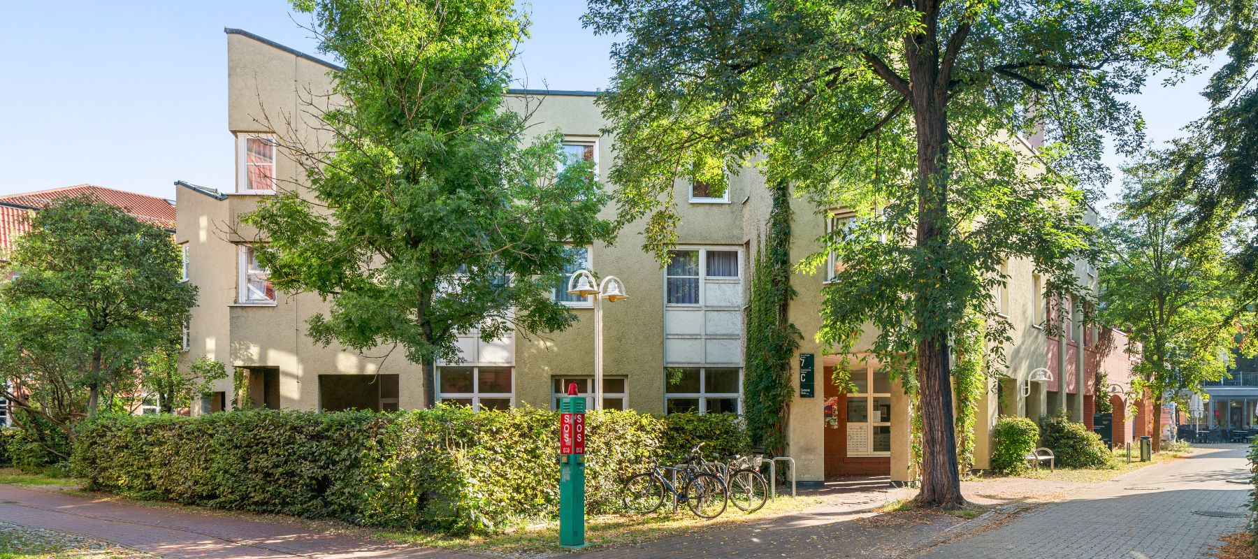 Eingang zum Wohnheim Nora-Platiel-Straße 7. Auf dem Gehweg davor ist eine Notrufsäule der Universität Kassel.
