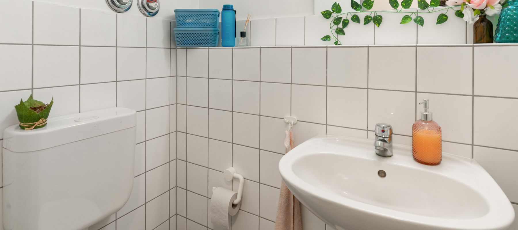 Gemeinschaftstoilette für Frauen in einer WG. Zu sehen ist ein Waschbecken sowie der Spülkasten einer Toilette.