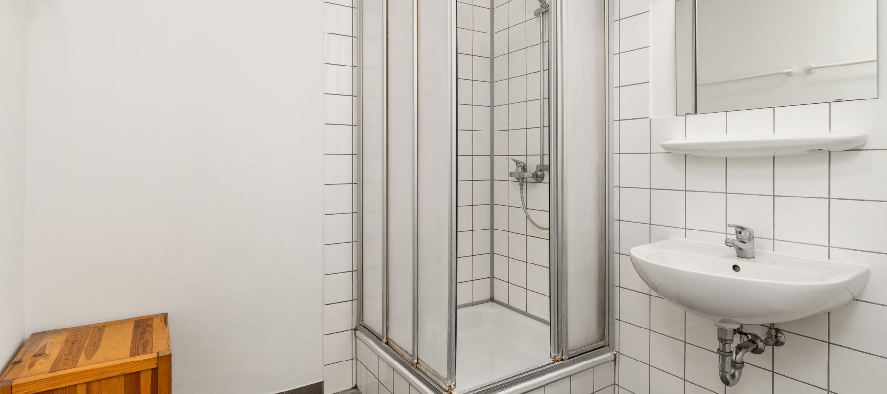 Gemeinschaftsdusche für Herren in WG. Zu sehen ist die Dusche sowie ein Waschbecken.