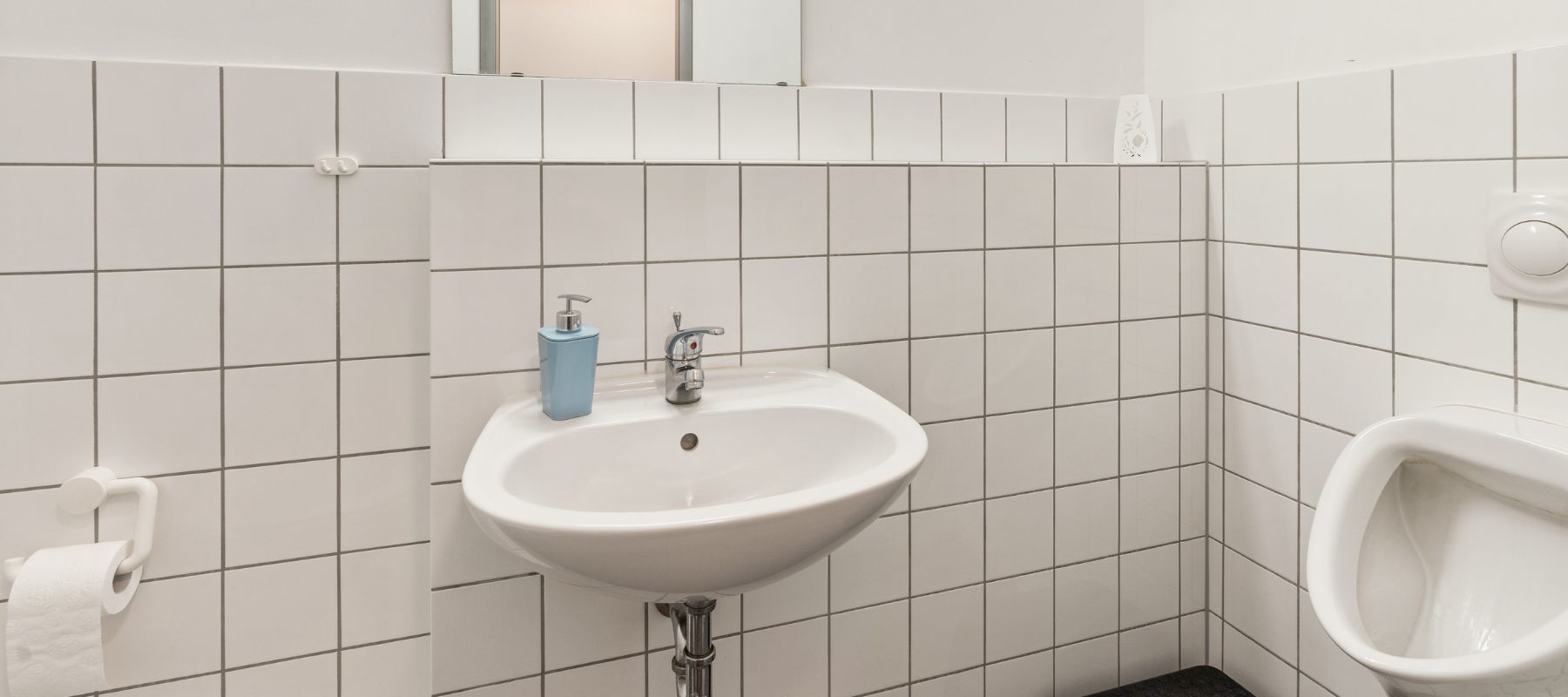 Gemeinschaftstoilette für Herren in WG. Zu sehen sind Waschbecken, Urinal und der Anschnitt einer Toilette.