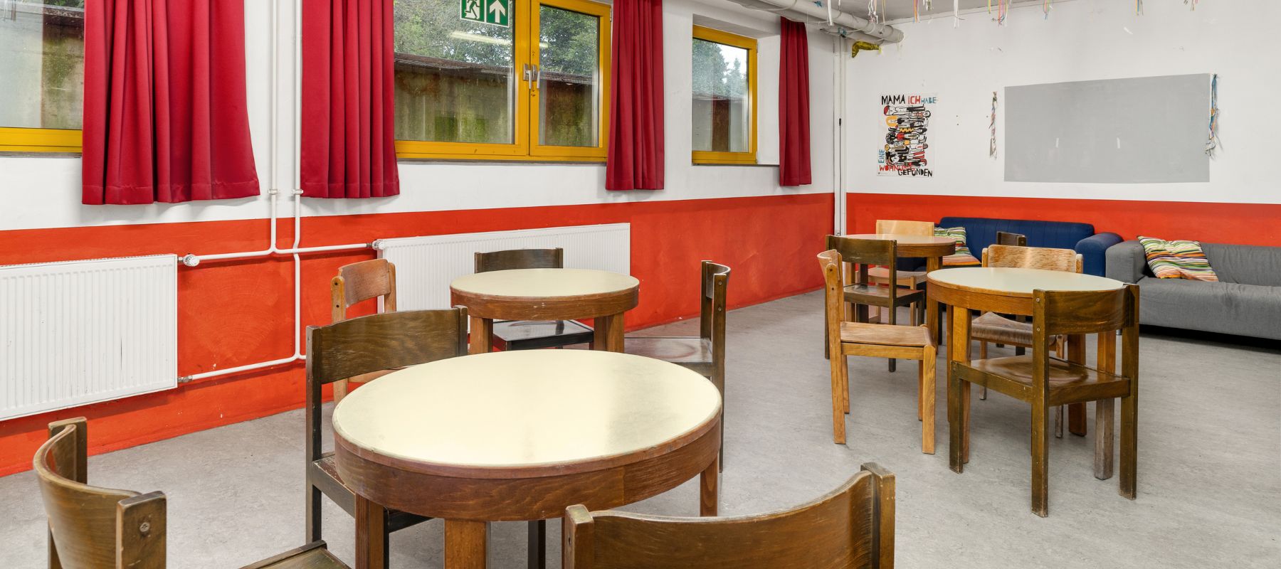 Gemeinschaftsraum im Wohnheim. Neben Tischen und Stühlen sind auch Sofas auf dem Bild.