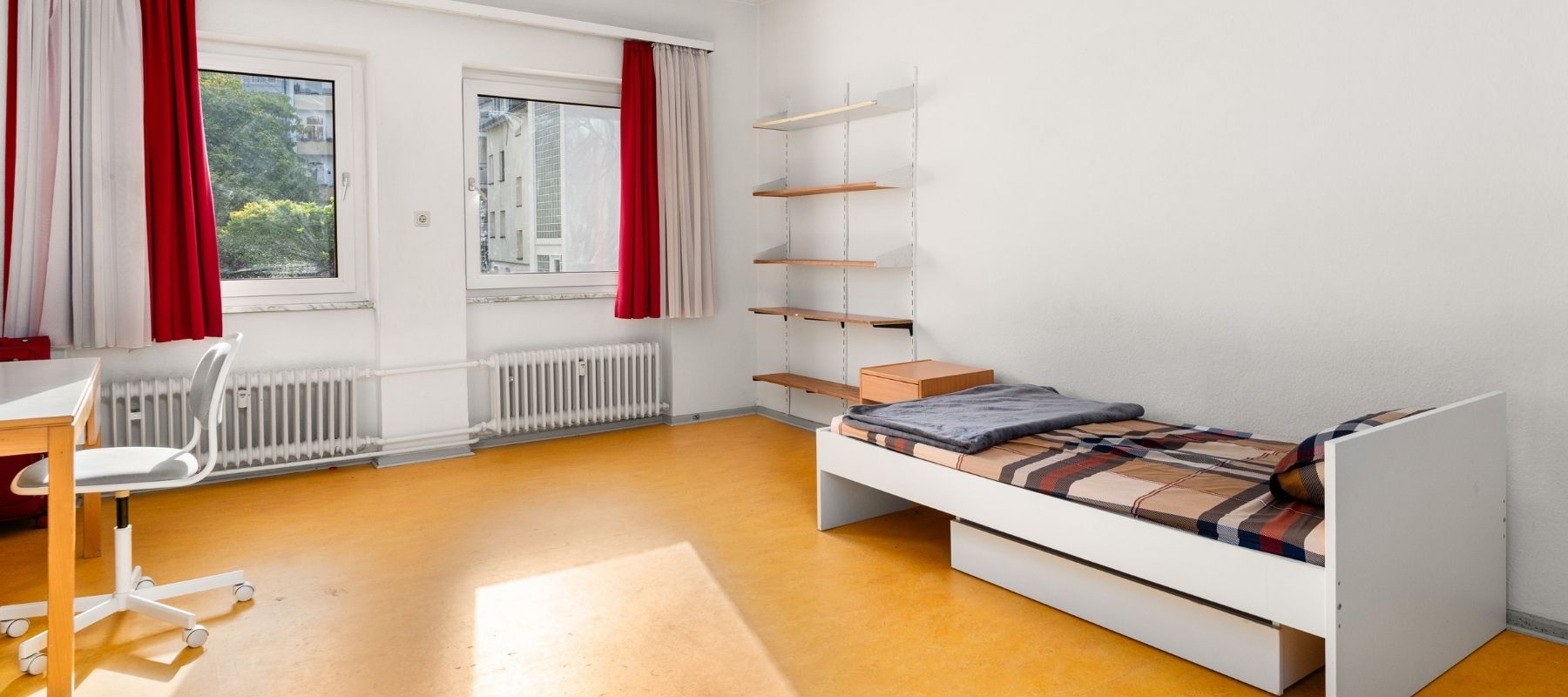 Helles WG-Zimmer mit Bett und Regal.