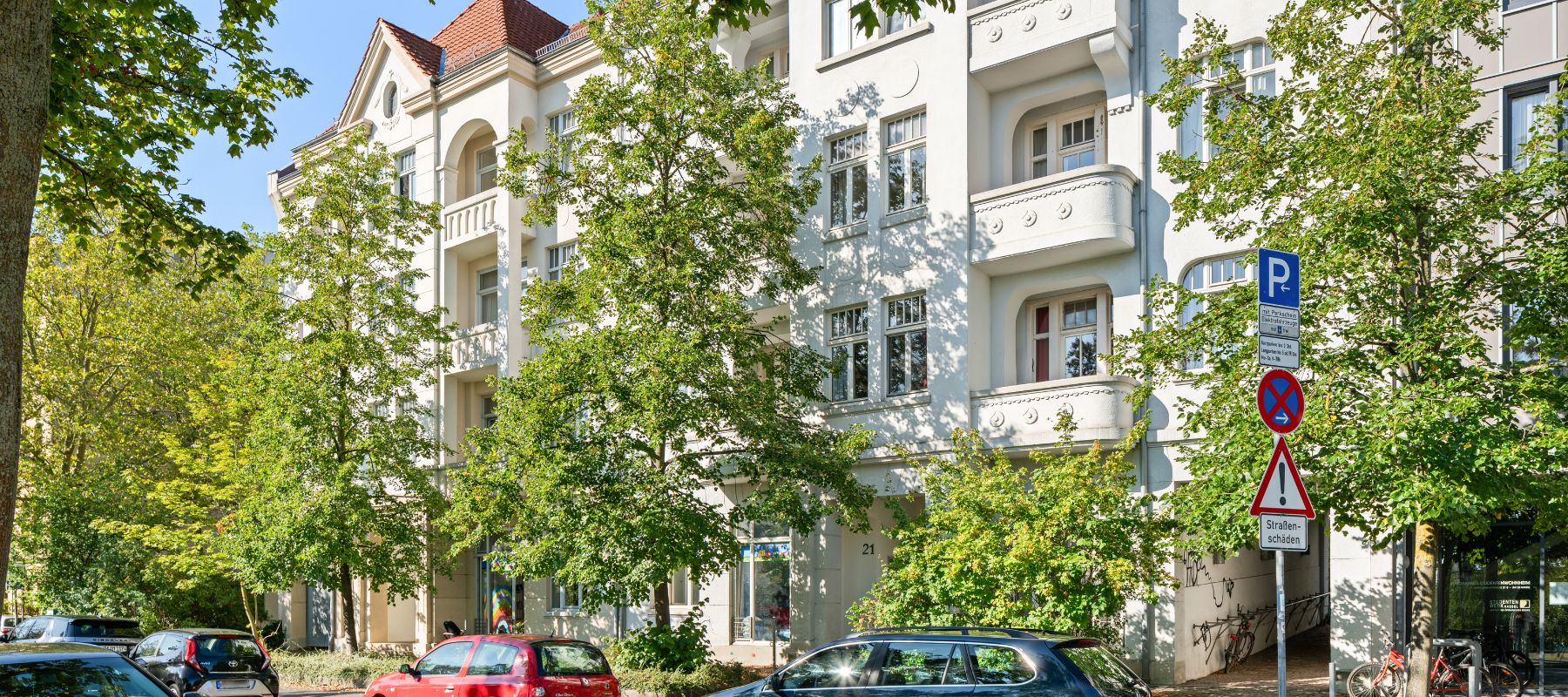 Außenansicht des Wohnheims. Cremefarbene Altbaufassade mit hohen Fenstern. Vorm Gebäude stehen Bäume.