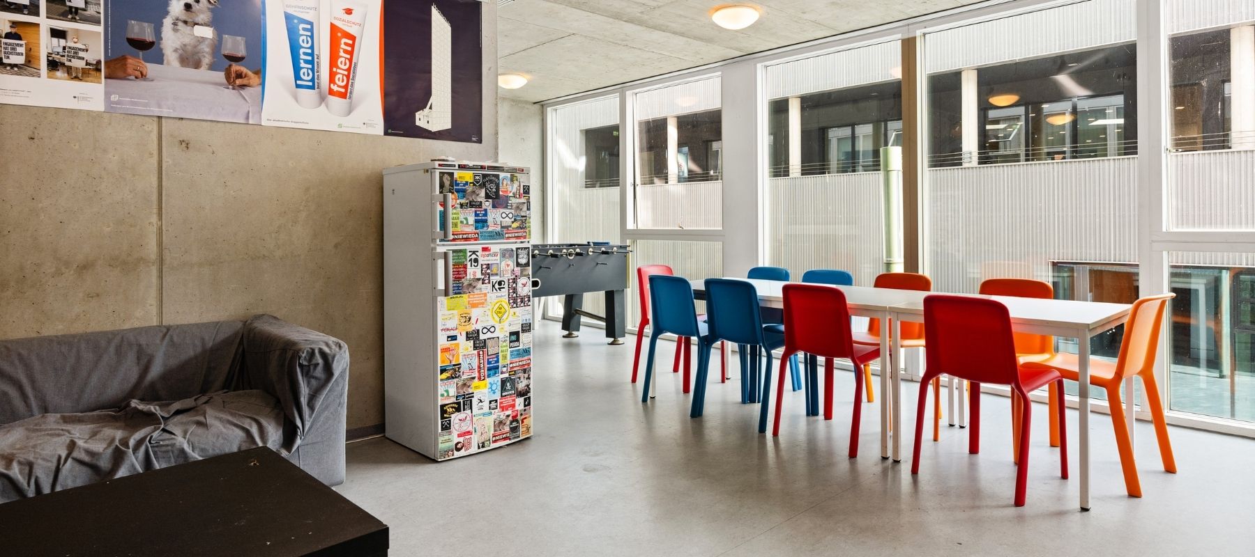 Großer Gemeinschaftsraum des Max Kade Hauses mit Sofa, Kühlschrank, Kickertisch, Tischen und Stühlen.