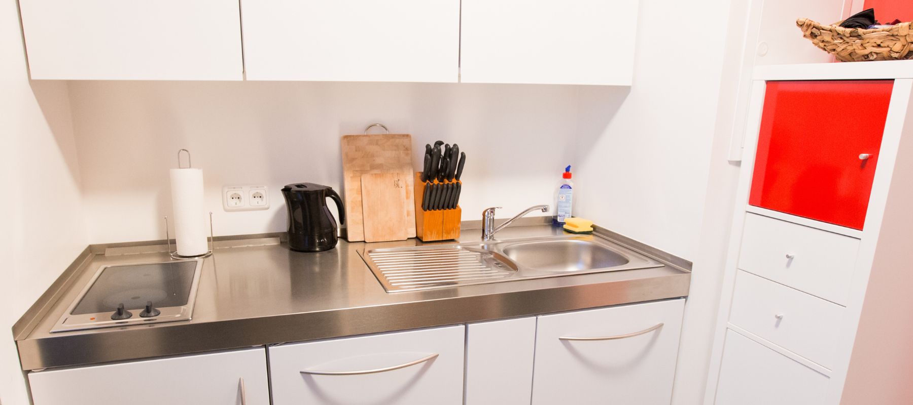 Detailaufnahme der Küchenzeile im Einzelapartment. Die Oberfläche ist aus Edelstahl. Die Herdplatte hat zwei Kochfelder. Es gibt keinen Backofen.