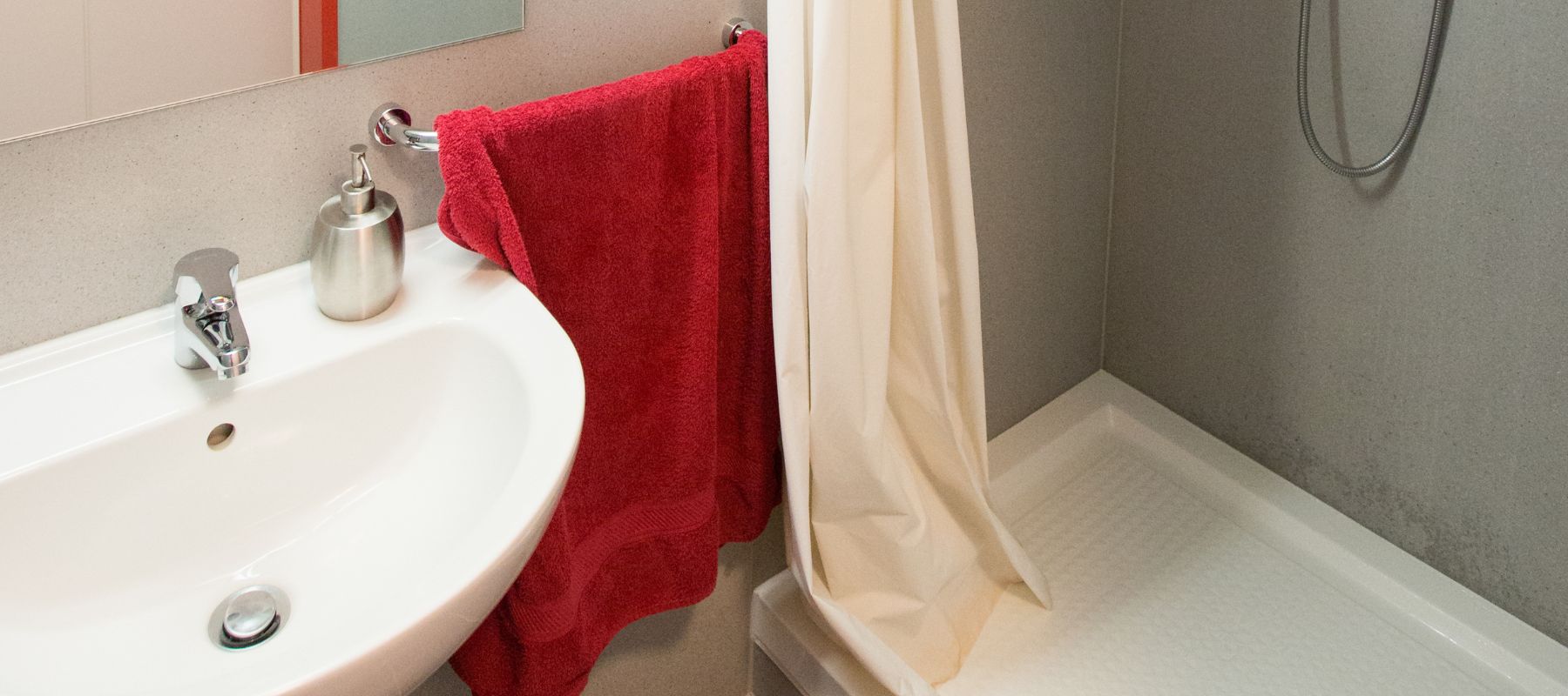 Details des Badezimmers: Zu sehen sind Spiegel, Waschbecken und eine Dusche.