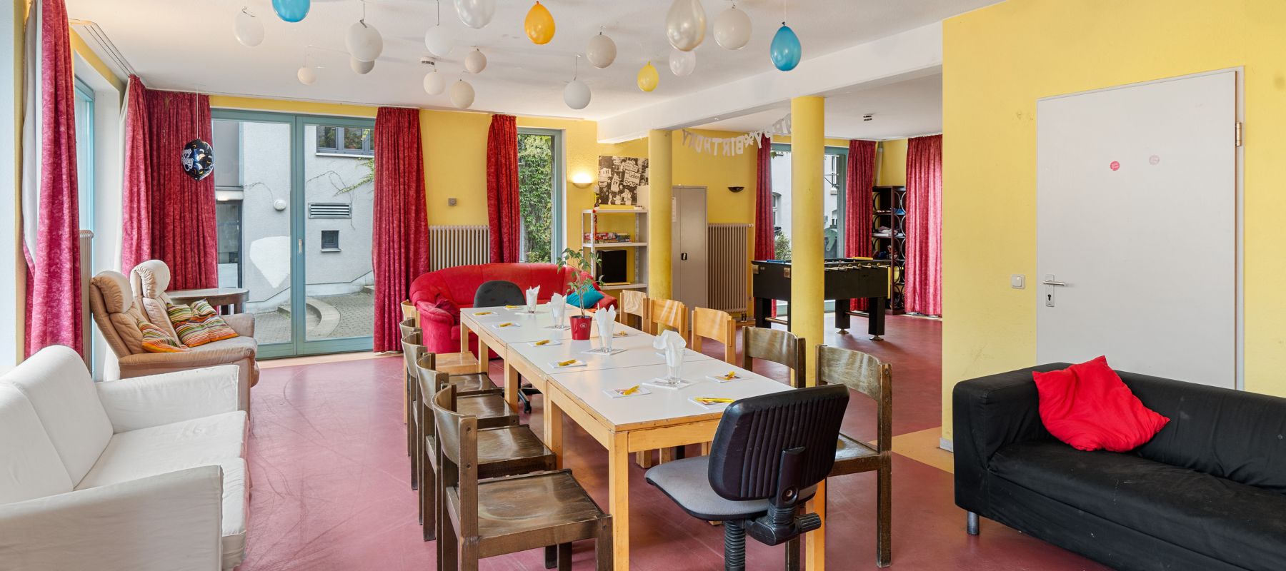 Gemeinschaftsraum des Wohnheims mit Sofas, Tischen, Stühlen und Sesseln.