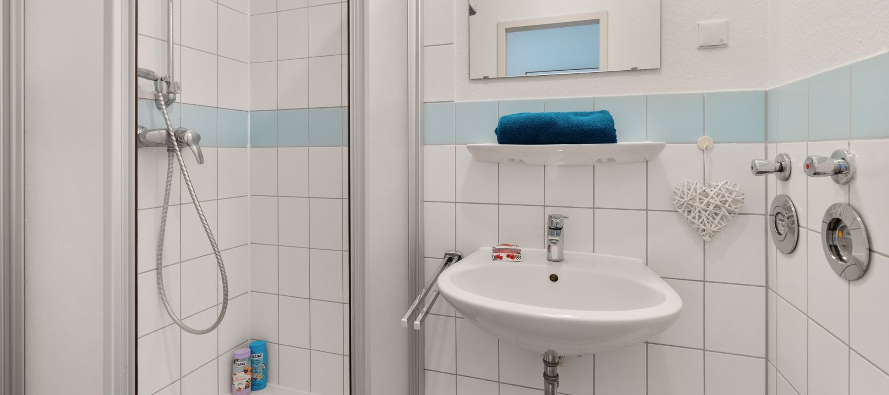Badezimmer eines Einzelapartments. Zu sehen ist ein Waschbecken und eine Dusche.