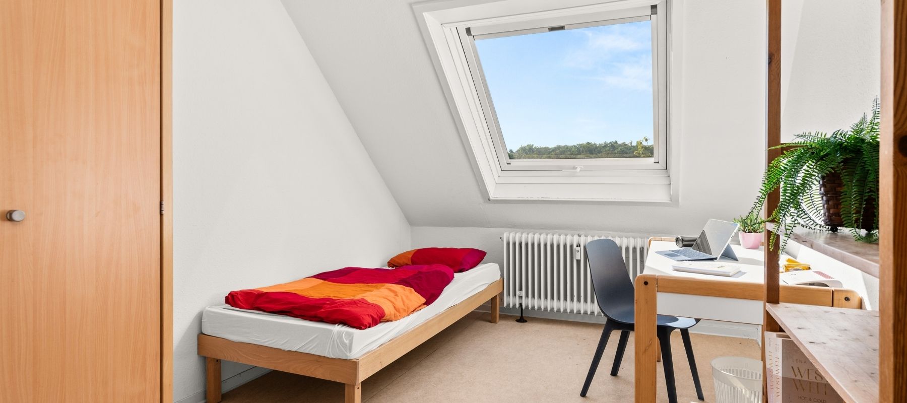 WG-Zimmer in der Naumburger Straße 15. Zu sehen sind ein Bett, ein Schreibtisch mit Stuhl, ein Regal und ein Kleiderschrank.