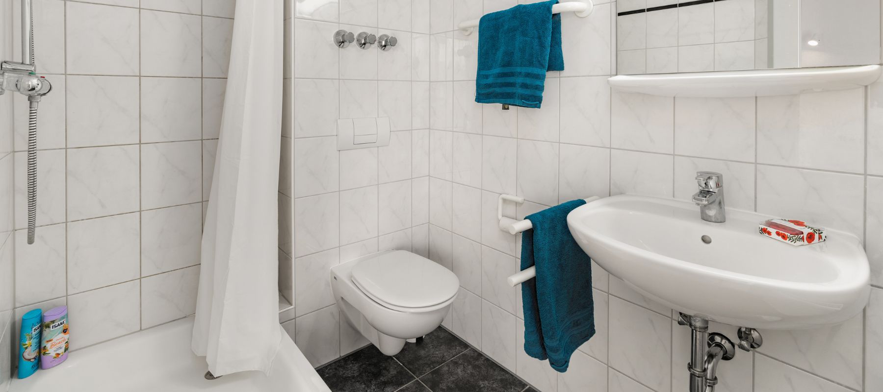 Badezimmer in einer WG mit Dusche, Toilette und Waschbecken.