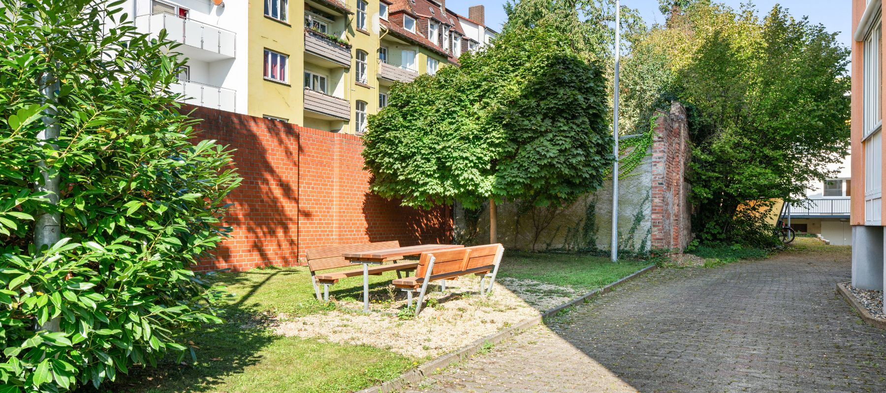 Sitzbereich mit zwei Bänken und einem Tisch außerhalb des Wohnheims.
