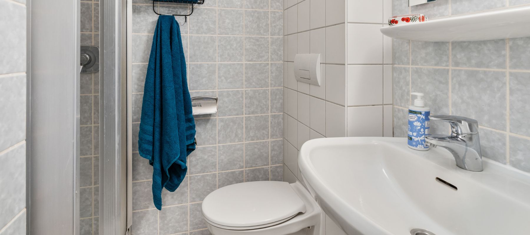 Badezimmer im Einzelapartment. Zu sehen sind Waschbecken, Toilette und Dusche.