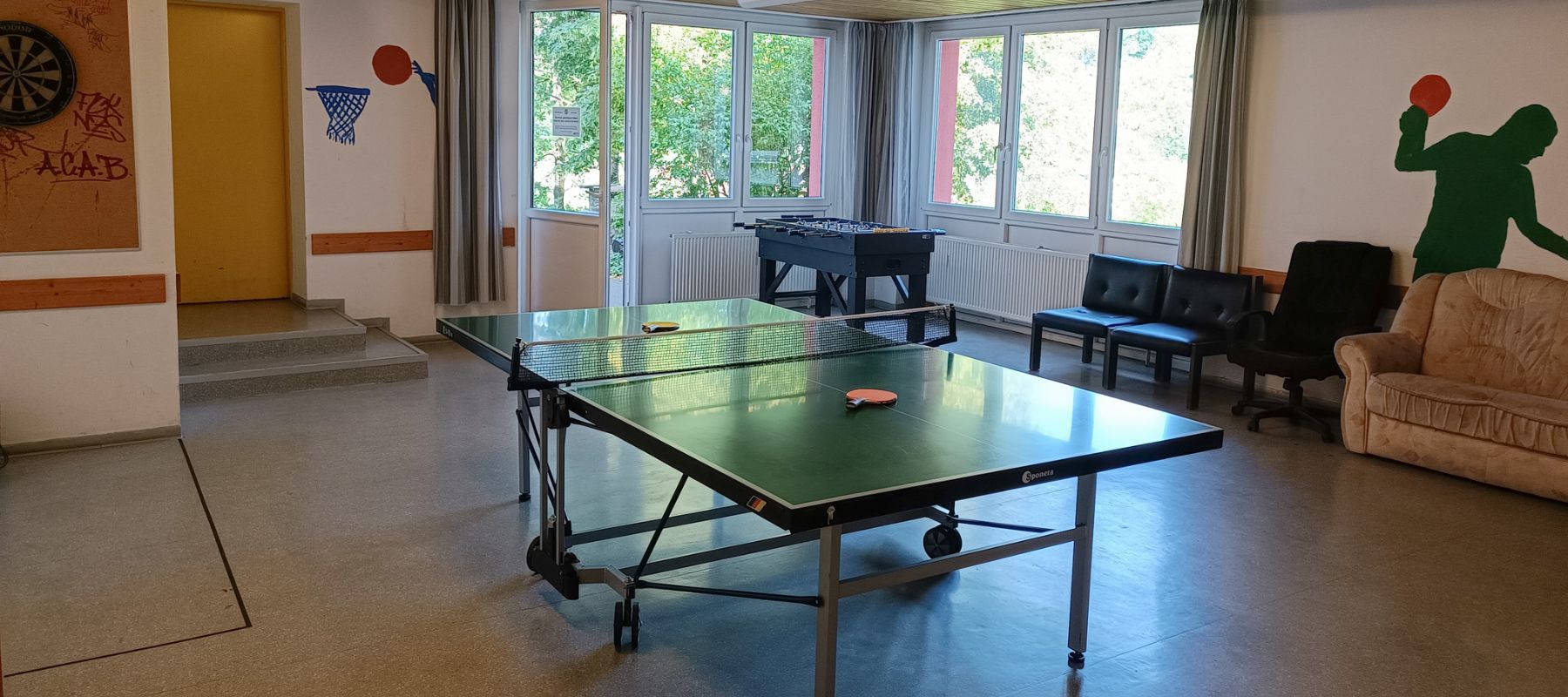 Gemeinschaftsraum mit einer Tischtennis-Platte und einem Kickertisch.