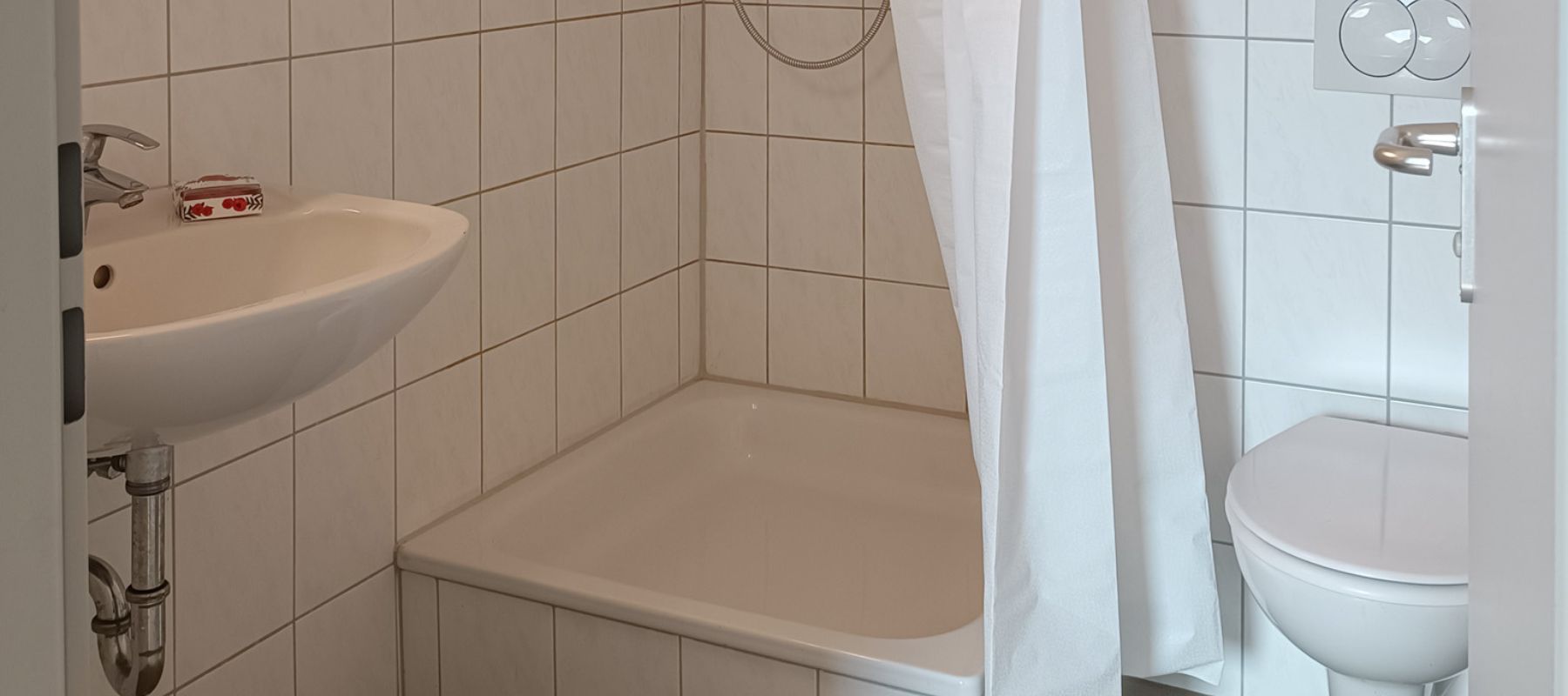 Badezimmers eines Einzelapartments. Zu sehen sind Dusche, Waschbecken und Toilette.